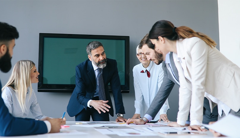 Hambre hablando con un grupo de personas con documentos sobre una mesa